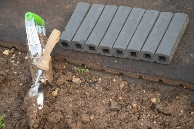 bricks and tools scattered about, in the process of building a walk way